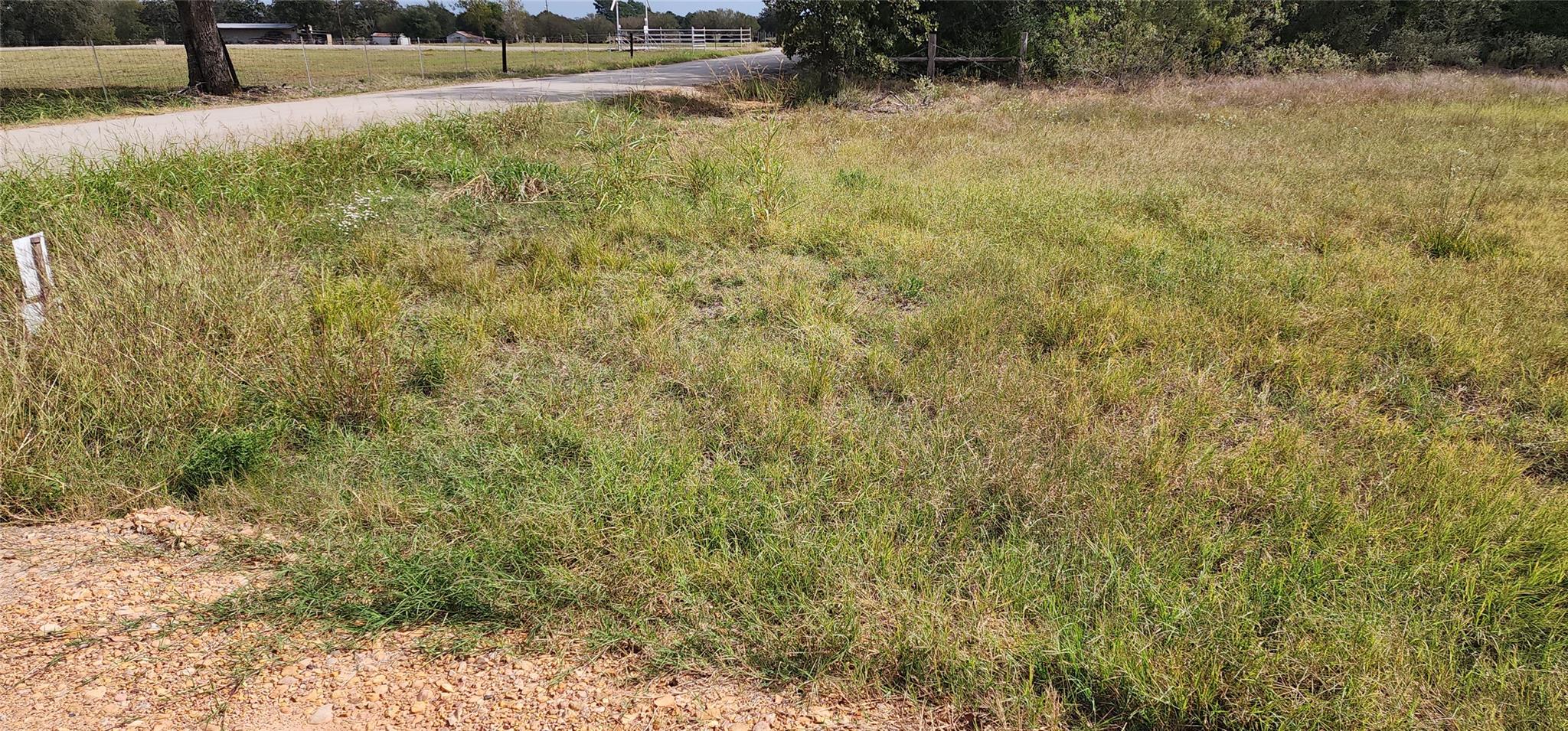 A quiet rural road borders this grassy, open lot 