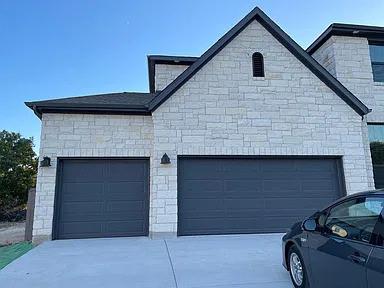 Textured light stone masonry surrounds dark garag