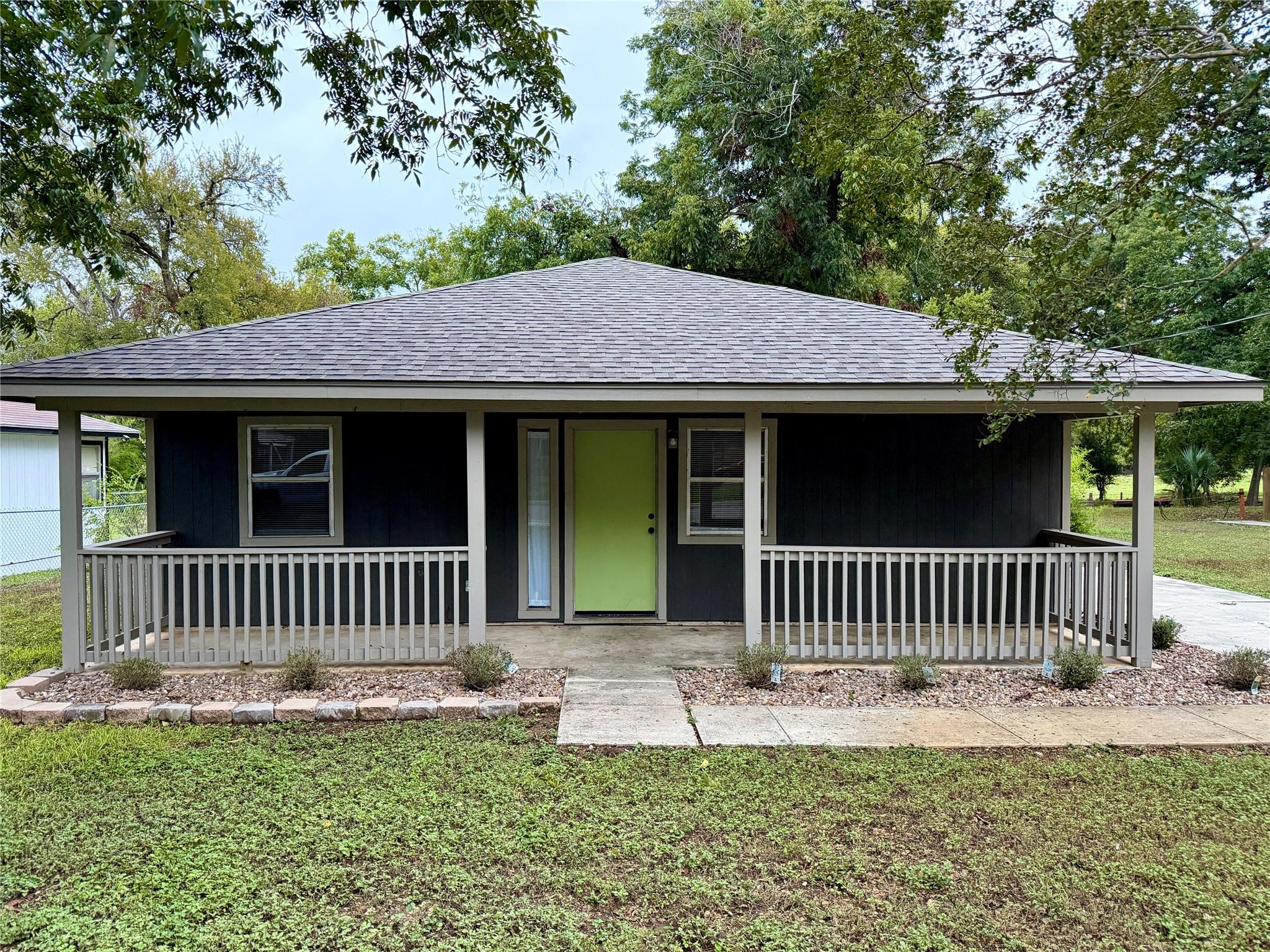 Mature trees frame a welcoming front porch with c