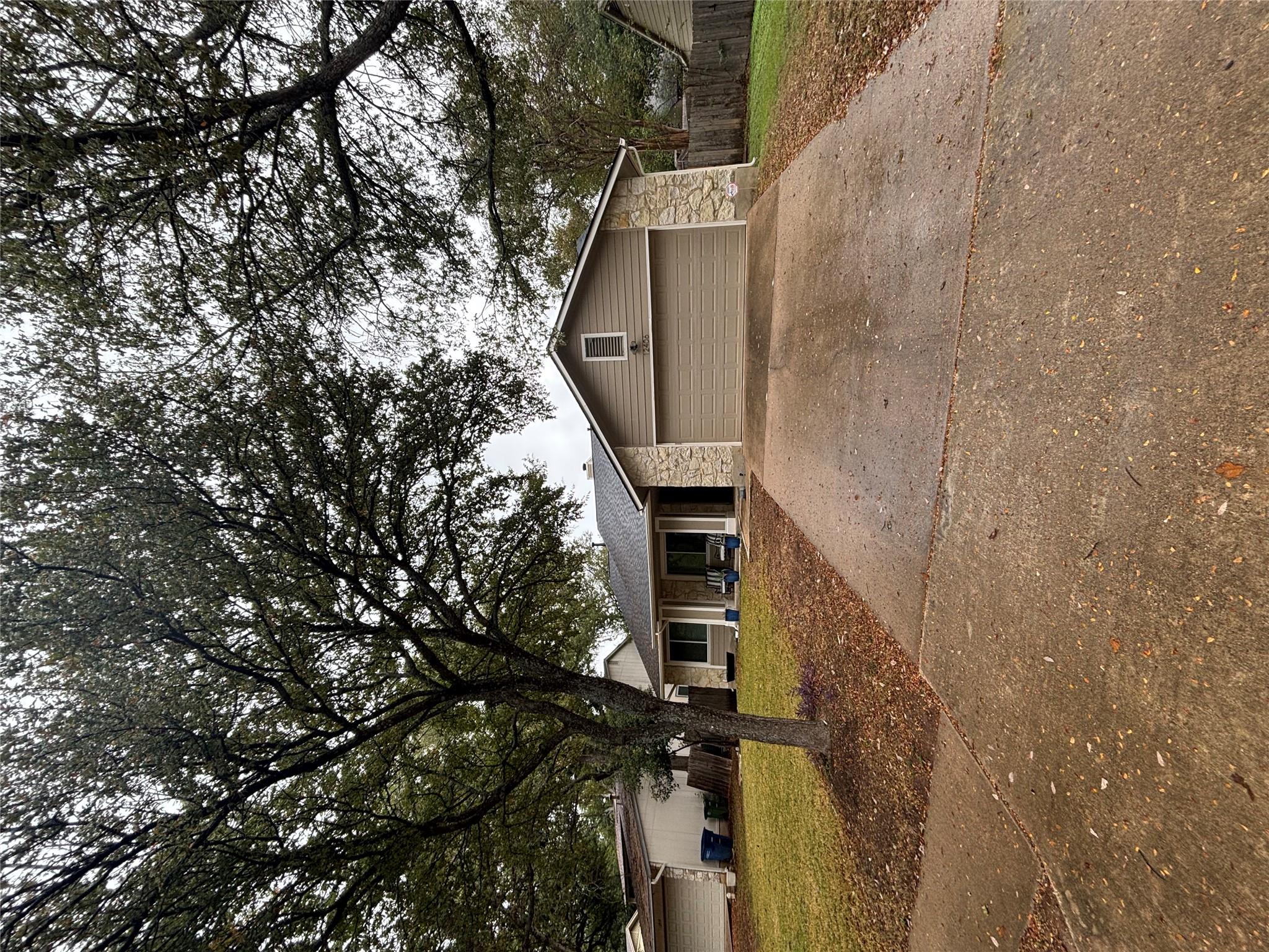 Mature trees shade a welcoming paved driveway lea