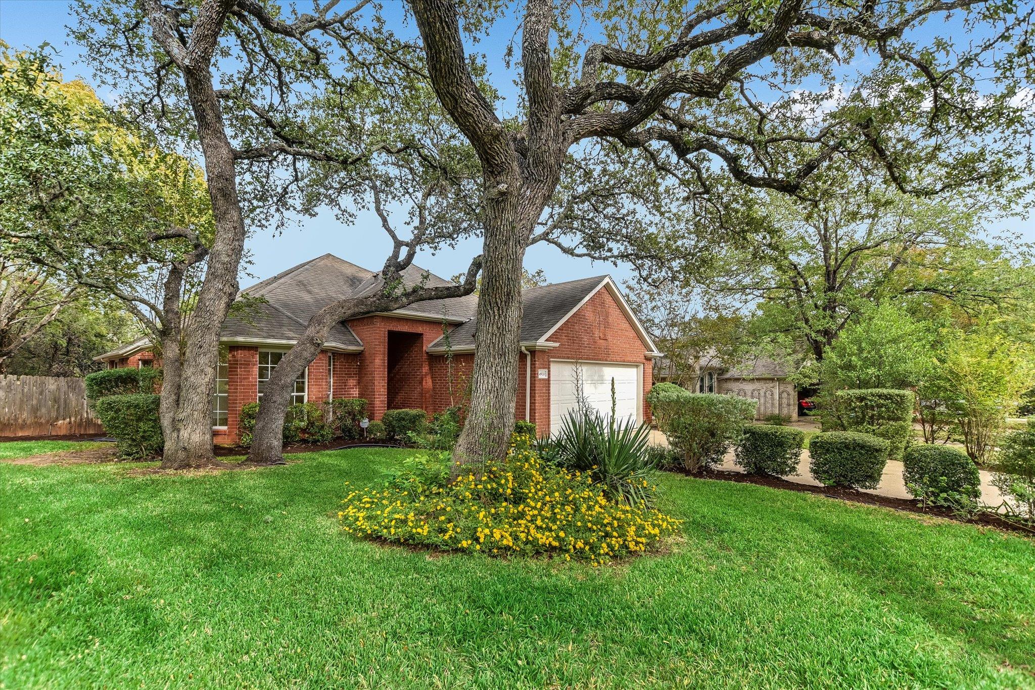 Mature oak trees shade the manicured lawn of this