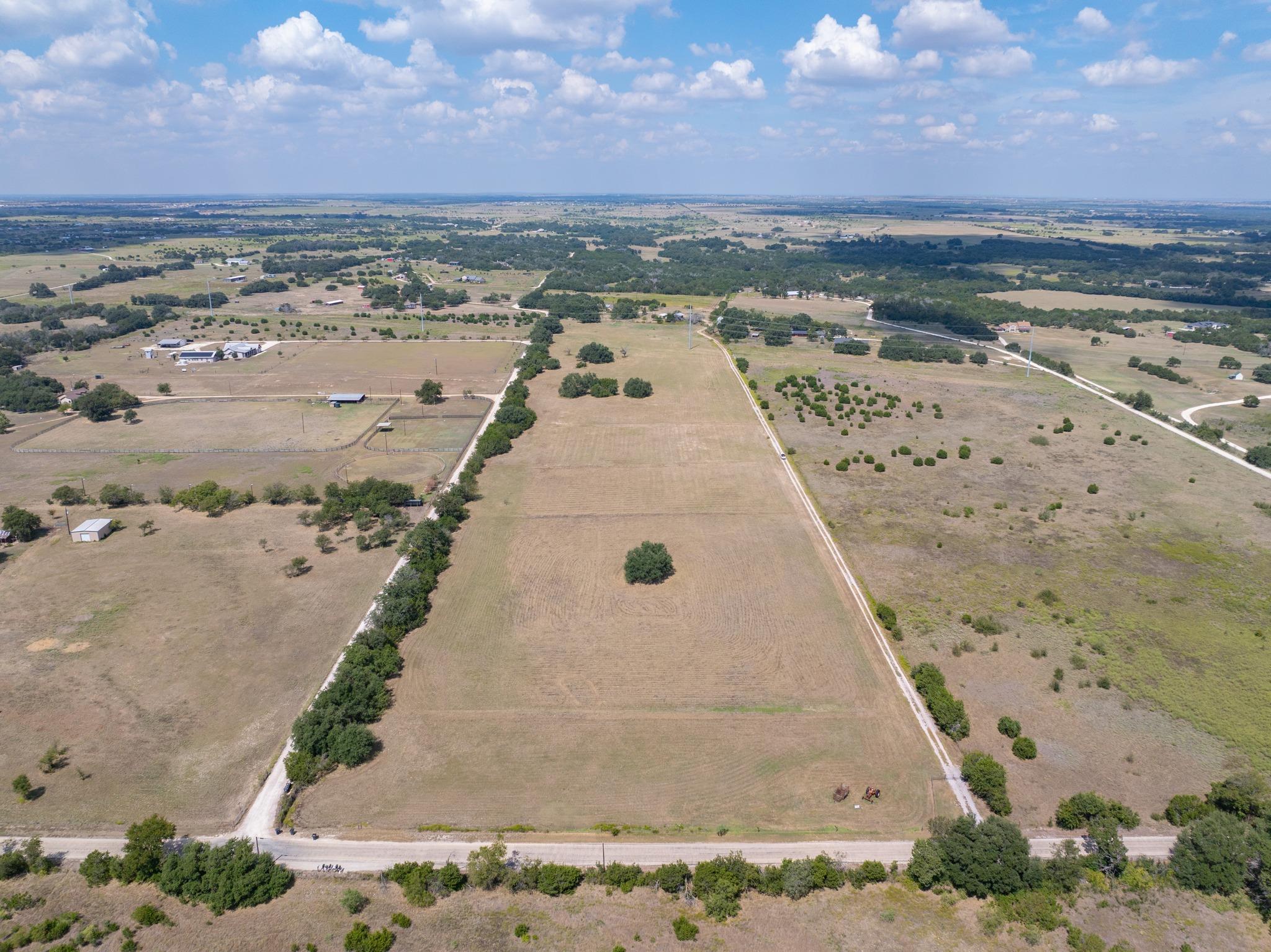 Vast open acreage bordered by mature trees stretc