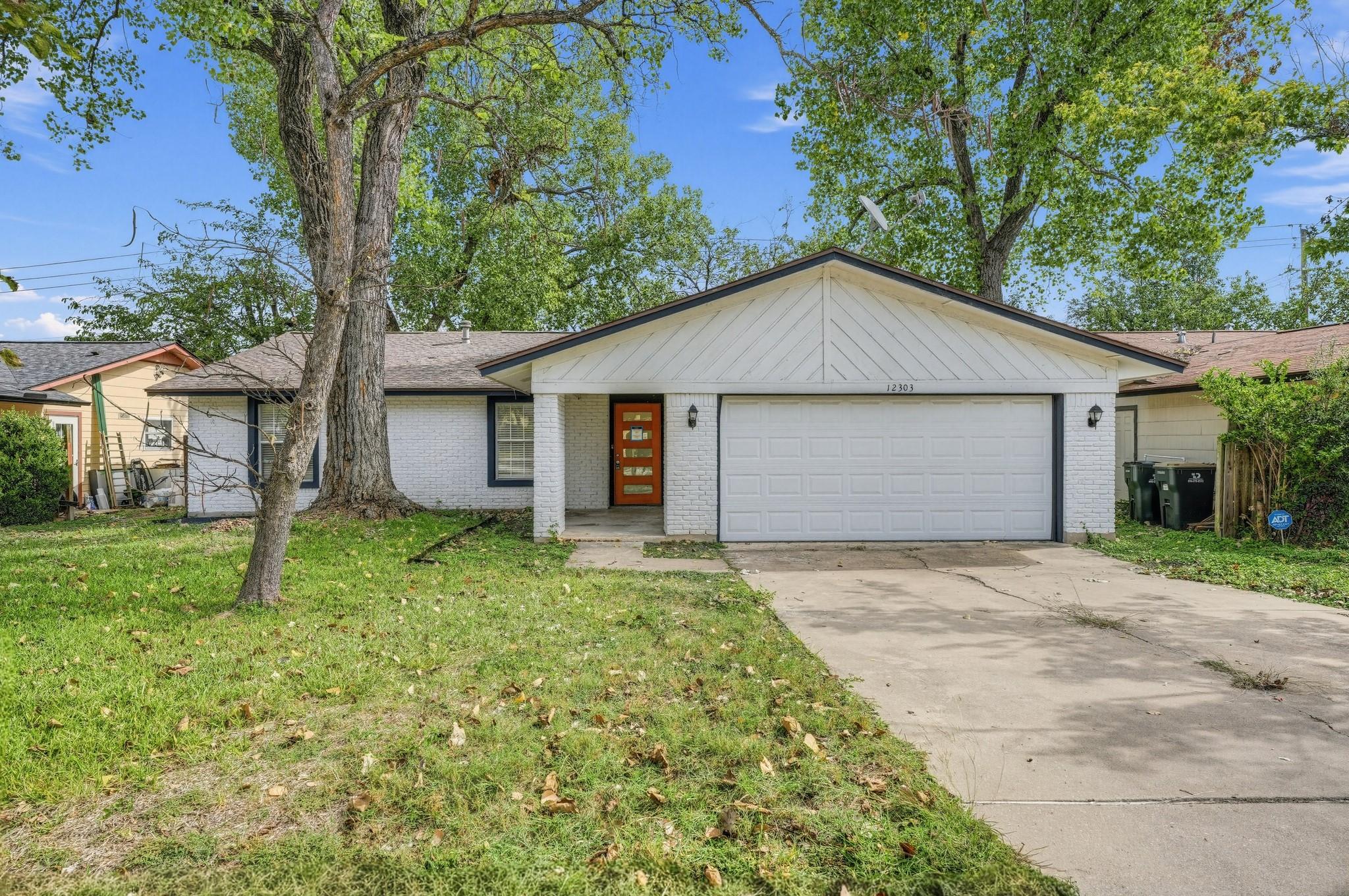 Mature trees shade the concrete driveway and welc