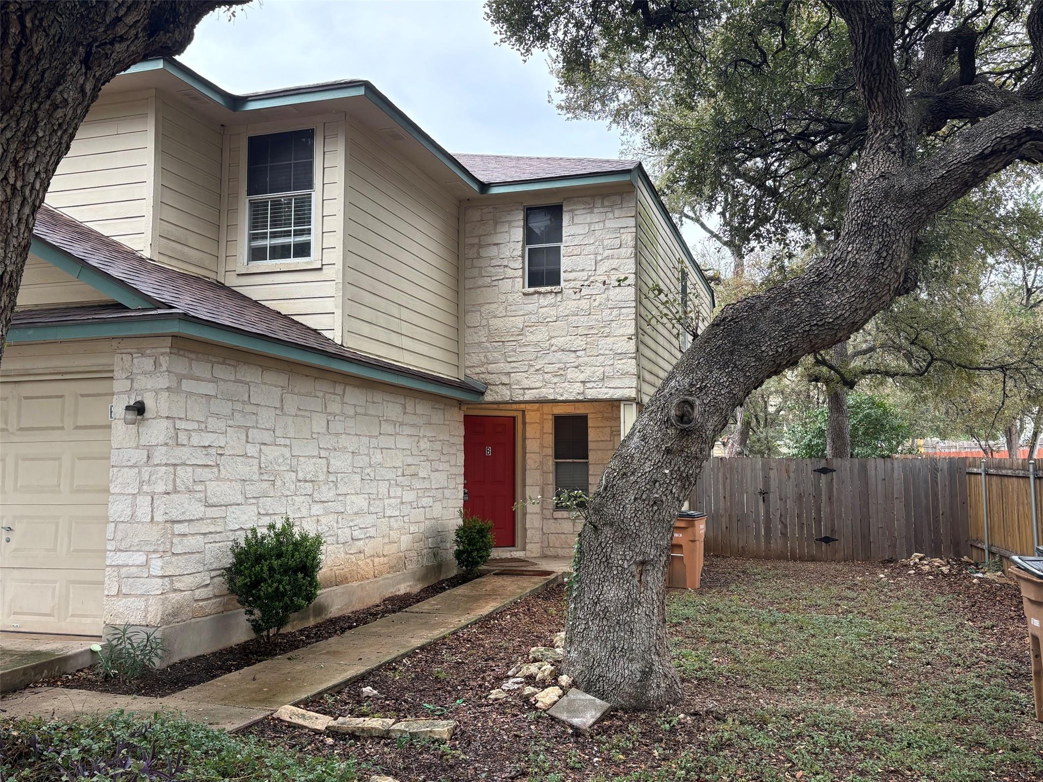 Mature trees shade a welcoming stone-and-siding e